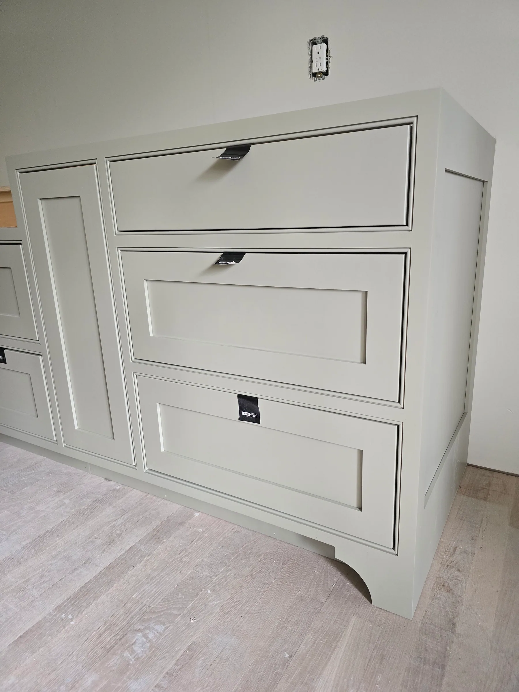 Painted cabinet drawers with framed fronts and a curved furniture foot at the base