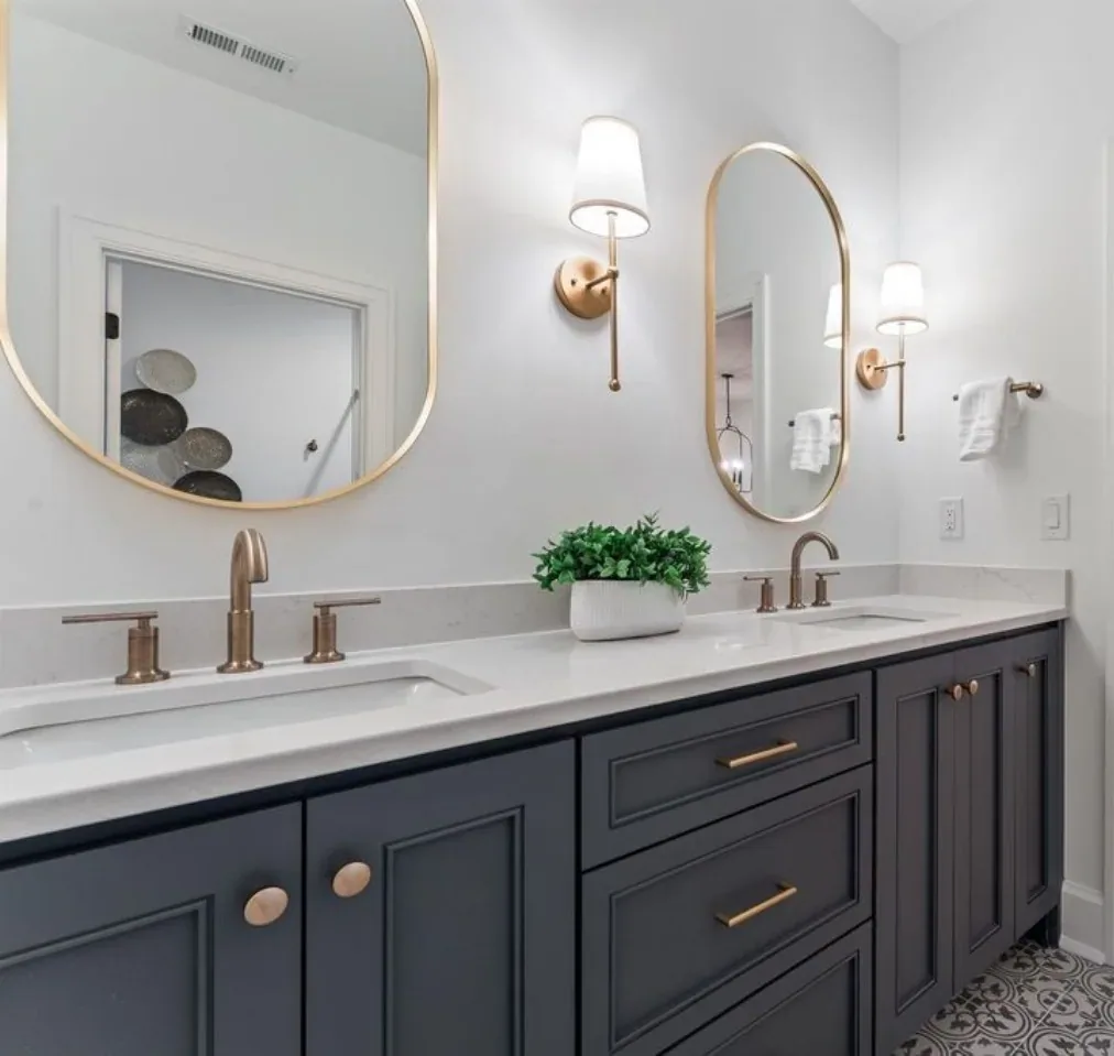 A navy painted double vanity with shaker doors, drawer stack, quartz top and brass pulls