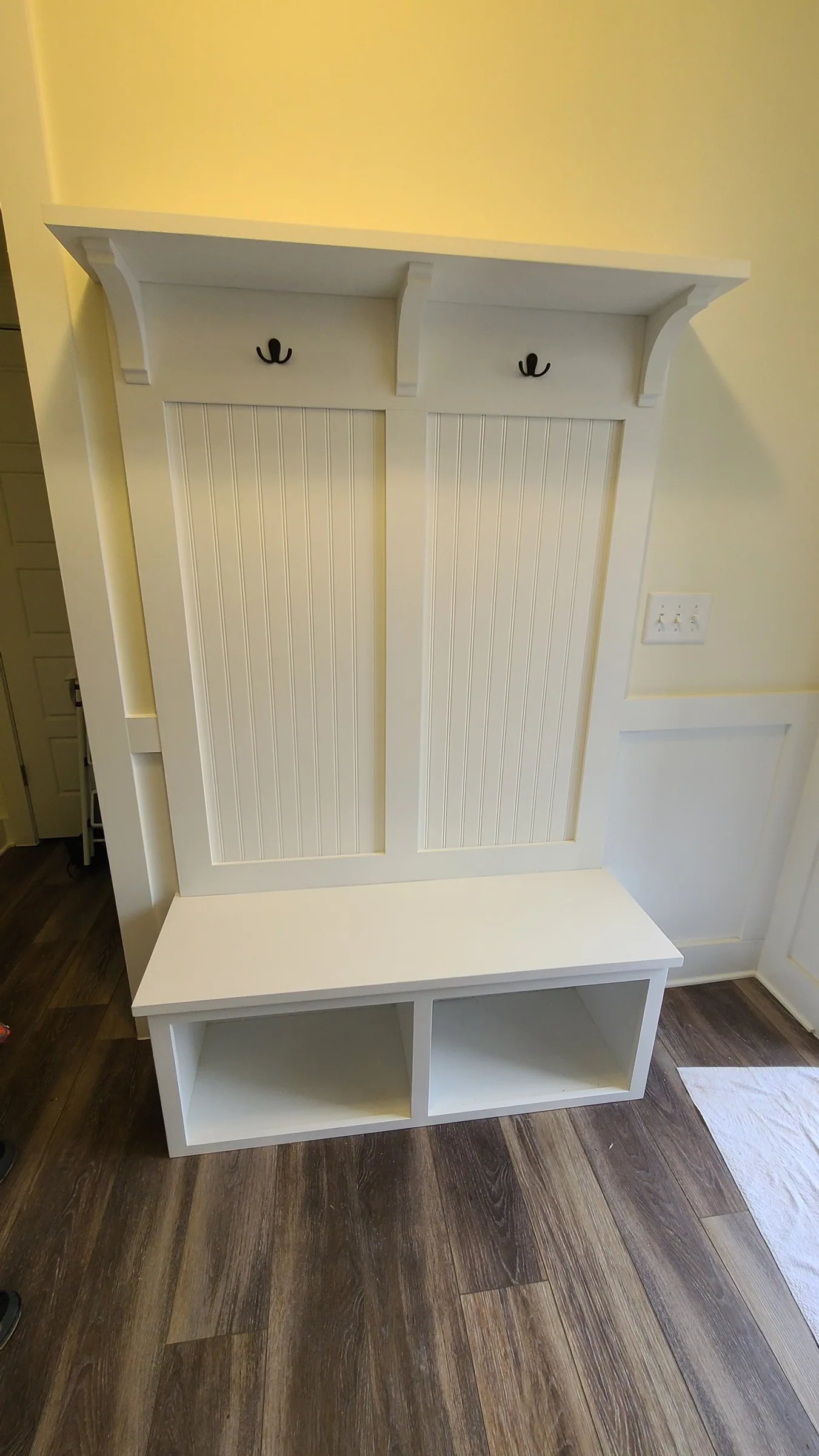 Painted hall tree with a beadboard back, coat hooks, a bench seat and open cubbies below
