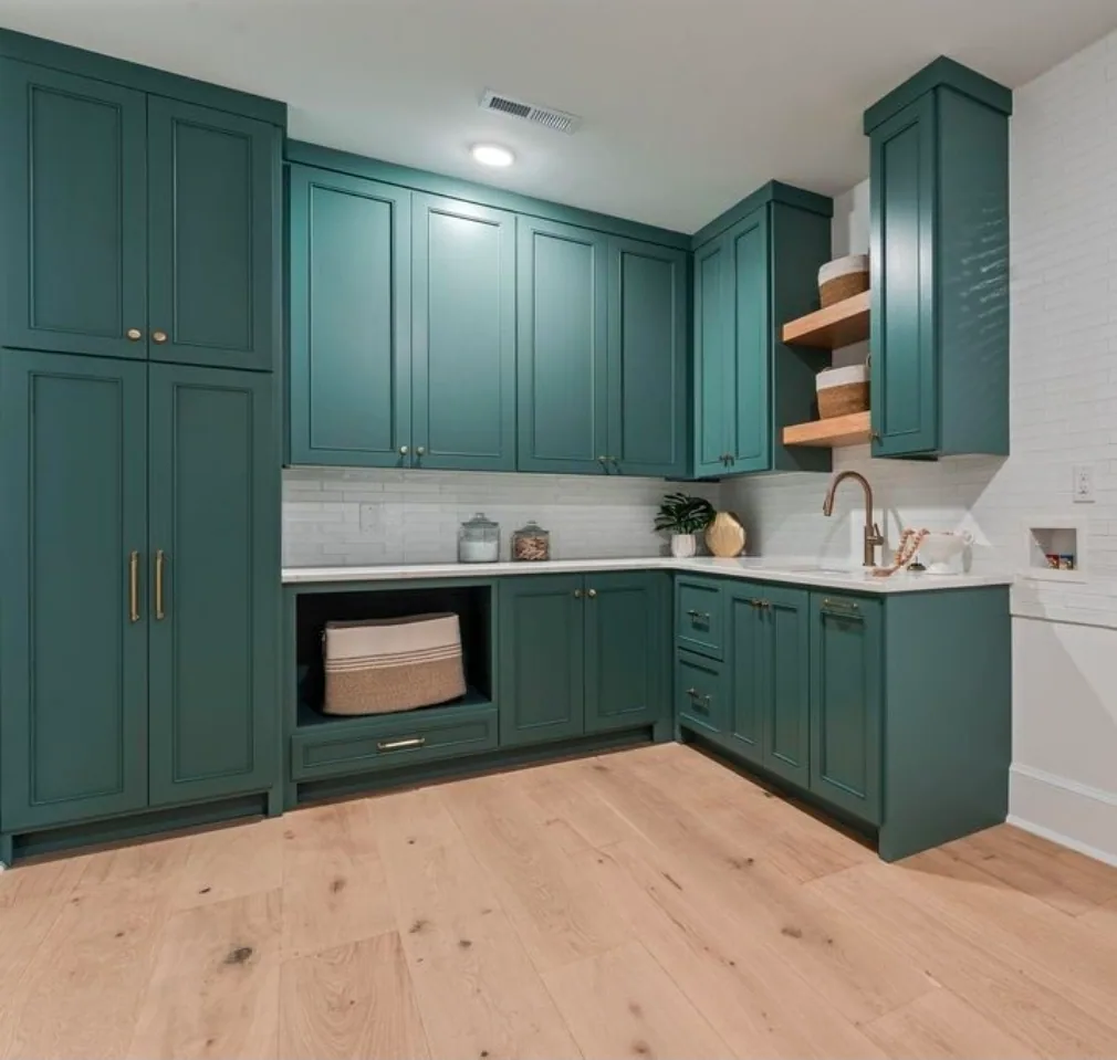 Laundry room with green painted cabinets to the ceiling, a white quartz counter, open oak shelves and an open cubby for a basket