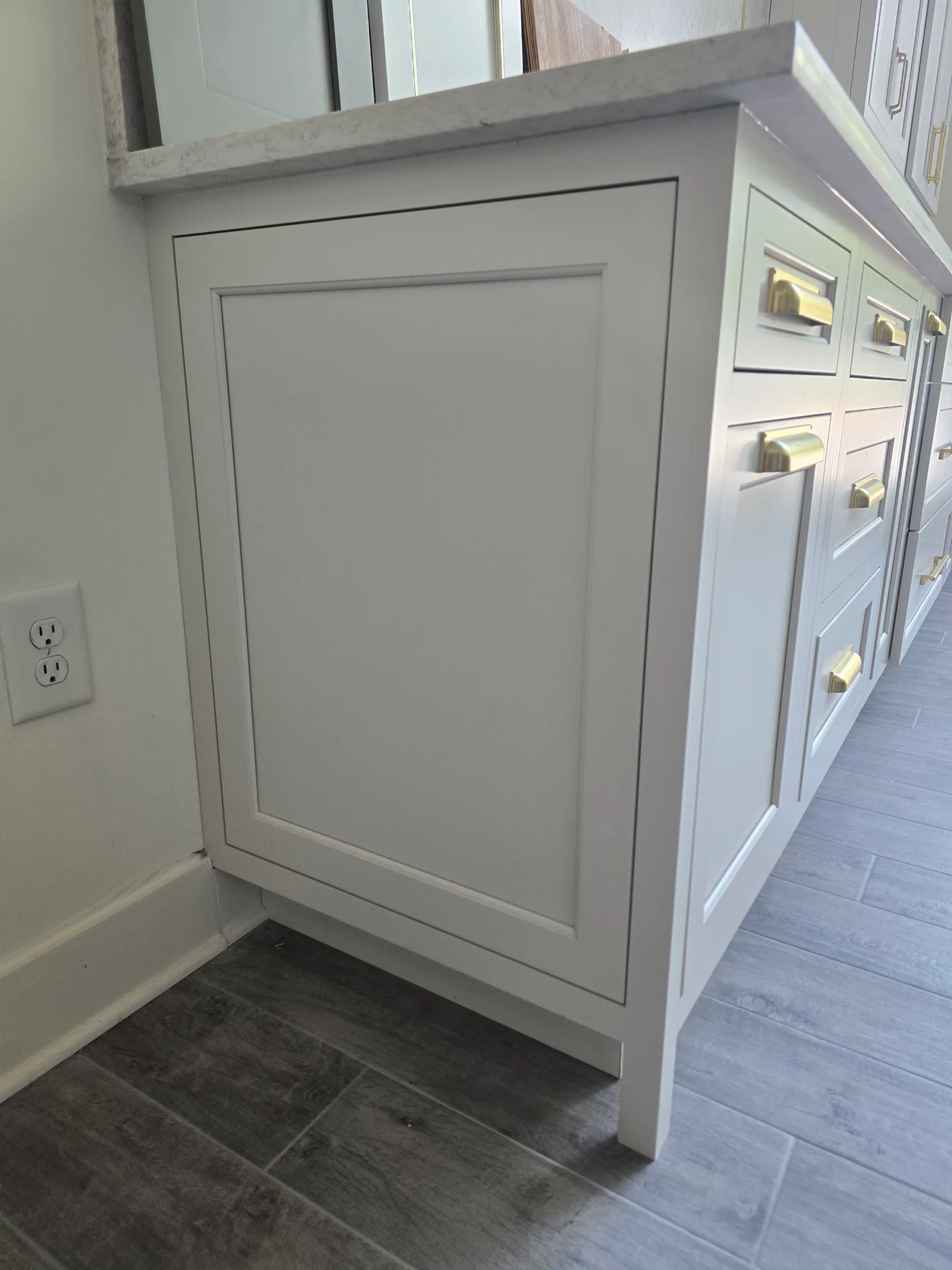Close up of a painted cabinet end with a framed panel, beside drawers with cup pulls